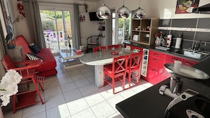 Une cuisine moderne aux touches de rouge, un coin repas avec un canapé rouge et une vue sur l’extérieur.