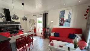 Un espace de vie moderne comprenant une cuisine, un coin repas et un canapé rouge.