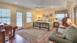 A bedroom with a bed, a desk, a chair, a sofa, and a large window. - Studio in College Station w/ Expansive Deck! (College Station)