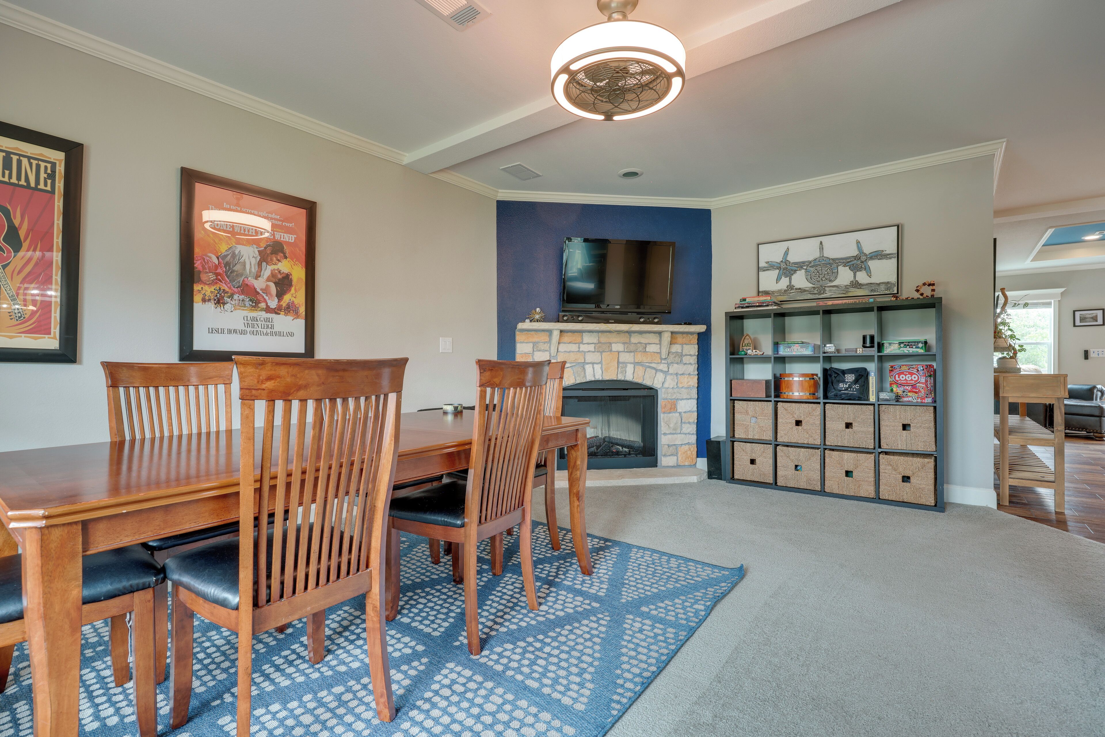 A dining area with a wooden table and chairs, a fireplace, and a built-in entertainment unit with shelves.