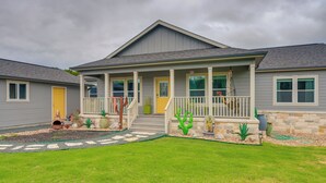Ein zweistöckiges Haus mit einer Veranda, einem kleinen Garten und einem Kiesweg, der zum Eingang führt.