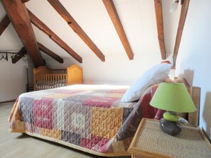 Un dormitorio con cama, mesita de noche, lámpara y cabecero de madera.