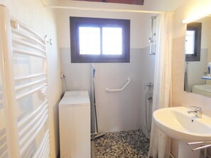 Un baño pequeño con ducha, inodoro y lavamanos.