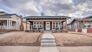A two-story building with a front porch, a central entrance, and a small front yard. - Charming Downtown Home w/ Updated Interior! (Oklahoma City)