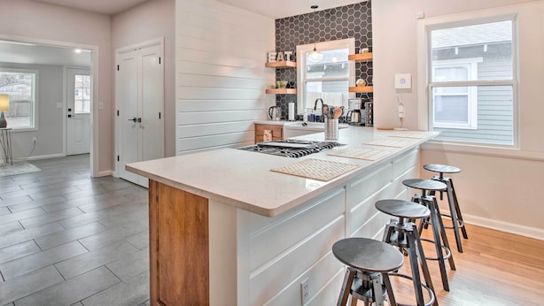 A modern kitchen with a central island, bar stools, and built-in shelves. - Charming Downtown Home w/ Updated Interior! (Oklahoma City)