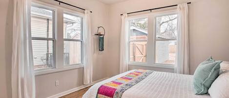 Ein Schlafzimmer mit zwei Fenstern, einem Bett mit Quilt und einem Deckenventilator.