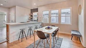 A modern kitchen with a central island, bar stools, and a dining table with chairs. - Charming Downtown Home w/ Updated Interior! (Oklahoma City)