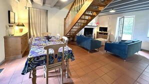 Un coin repas avec une table dressée pour quatre personnes, un canapé bleu et un escalier en bois.