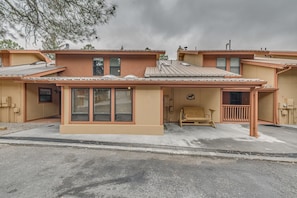 A two-story house with a covered porch, a small outdoor seating area, and a garage. - Ruidoso Condo w/ Hot Tub: Long Walk to Midtown! (Ruidoso)