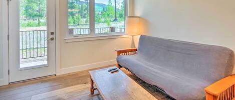 A room with a sofa, a wooden coffee table, a lamp, and a door leading to an outdoor balcony.
