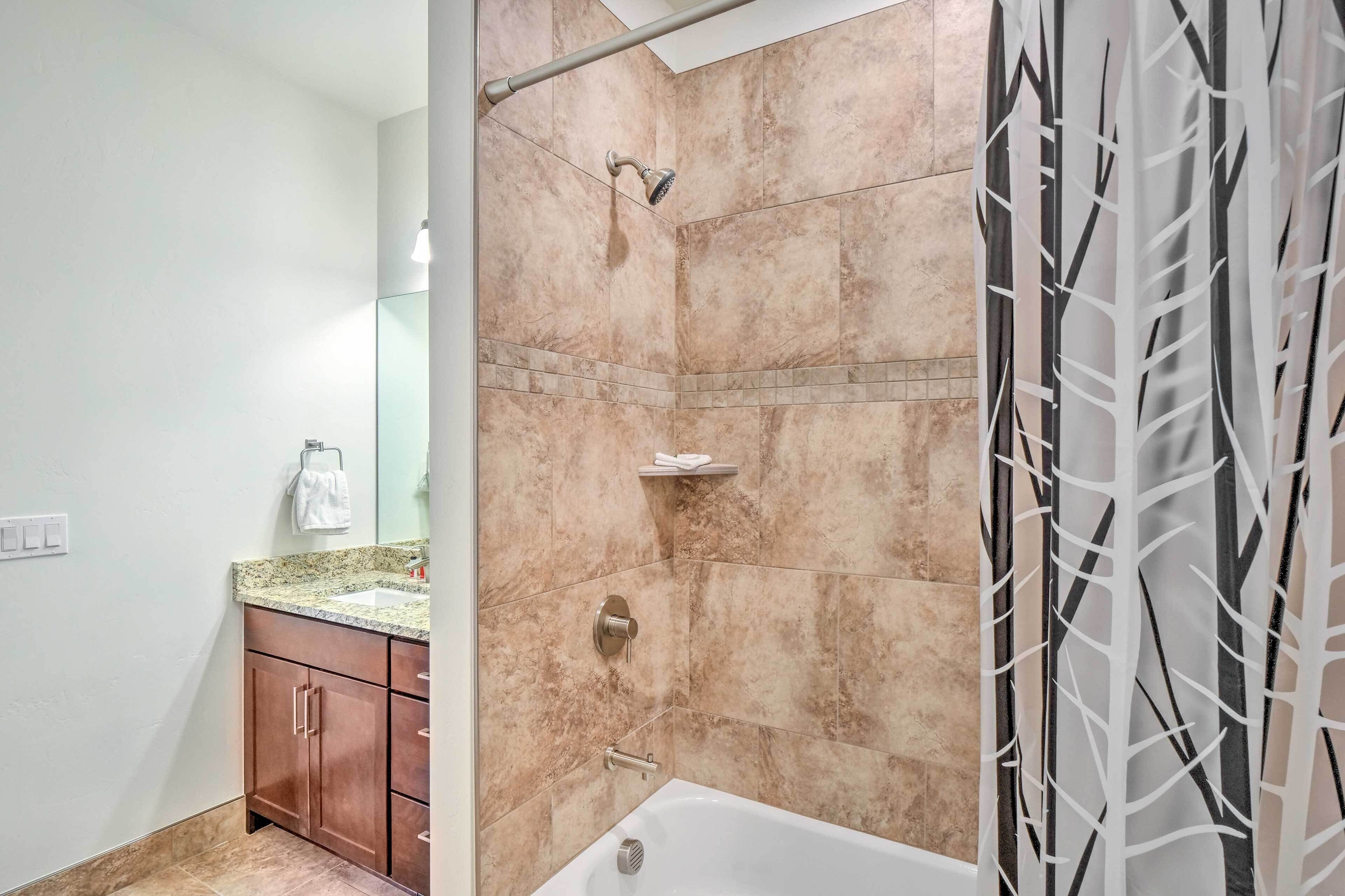 A bathroom with a shower, a sink, and a vanity with a mirror.