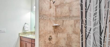 A bathroom with a shower, a sink, and a vanity with a mirror.