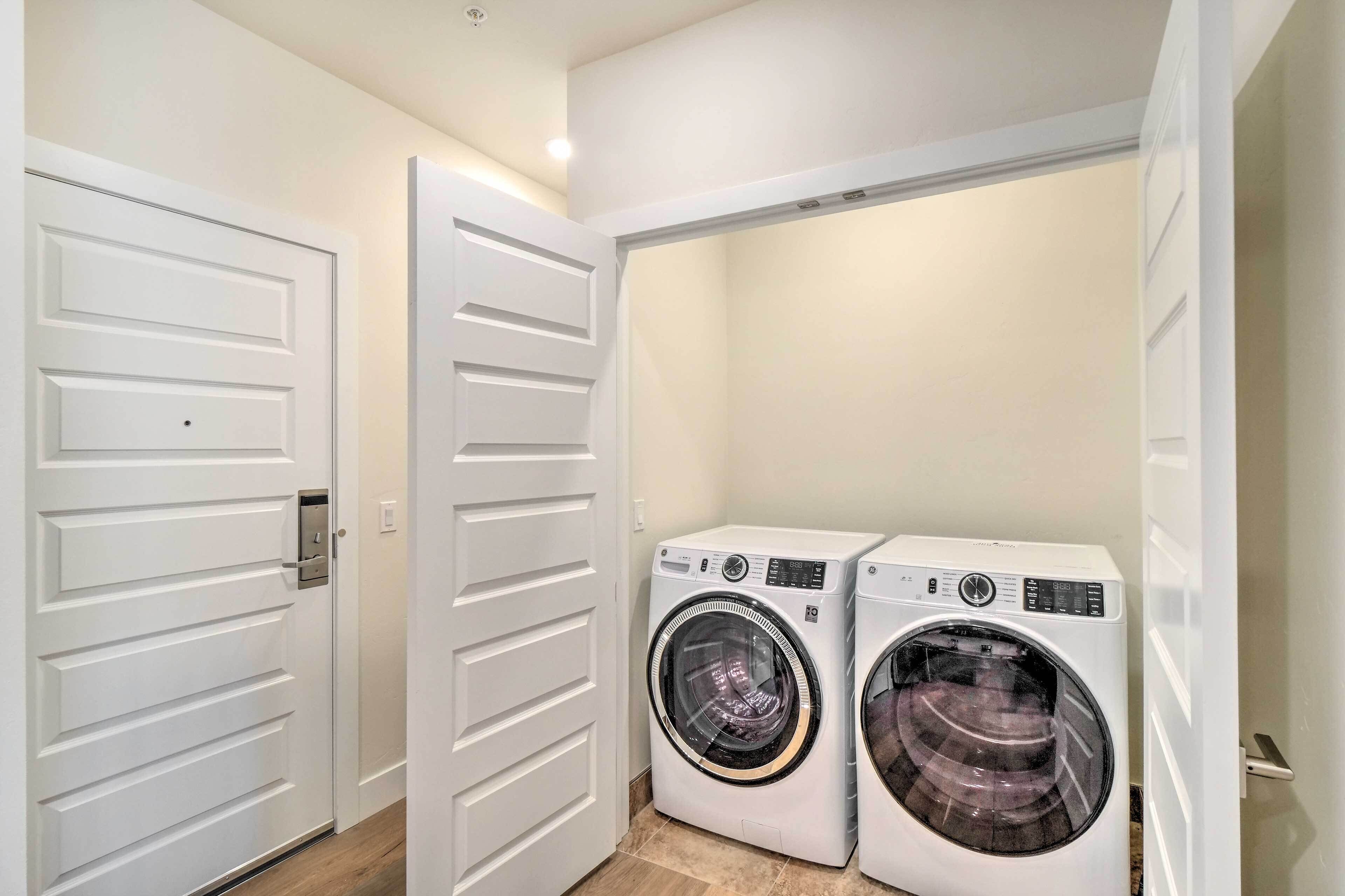 A laundry room with two front-loading washing machines and a white door with a handle.