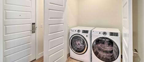 A laundry room with two front-loading washing machines and a white door with a handle.