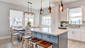A modern kitchen with a large island, bar stools, and pendant lighting.