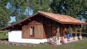 Ein rustikales Blockhaus mit Holzwänden und einem Ziegeldach, mit einer Terrasse, Sitzgelegenheiten im Freien und einem kleinen Garten.