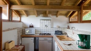 Eine kleine Küche mit Holzbalken, einer Mikrowelle, einem Gaskochfeld, einem Spülbecken und einer Kaffeemaschine.