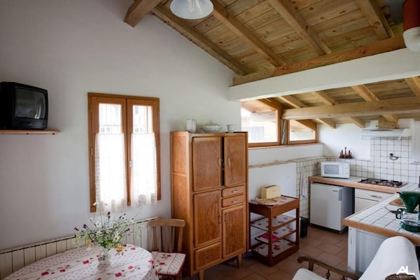 Una cocina con armarios de madera, un microondas y un refrigerador pequeño.