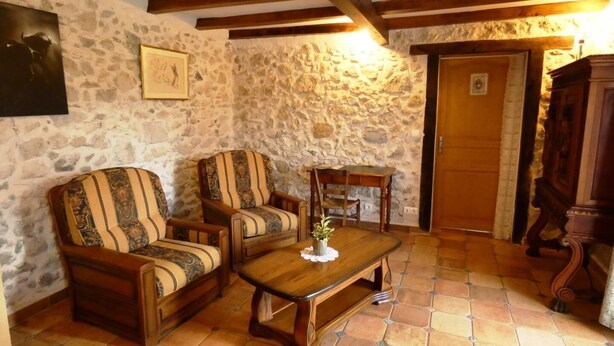 A rustic room with stone walls, wooden furniture, and a tiled floor.
