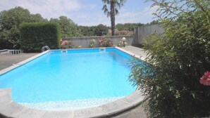A rectangular swimming pool with a clear blue water surface, surrounded by a stone deck.