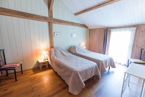 A room with two beds, wooden floors, a small table, and a chair. - Safranério - Vert - Gîte (VERT)