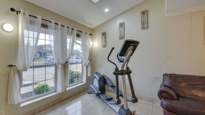 A room with a window, curtains, an exercise machine, and a leather sofa. - Cozy Oklahoma City Home w/ Deck & Gas Grill! (Oklahoma City)