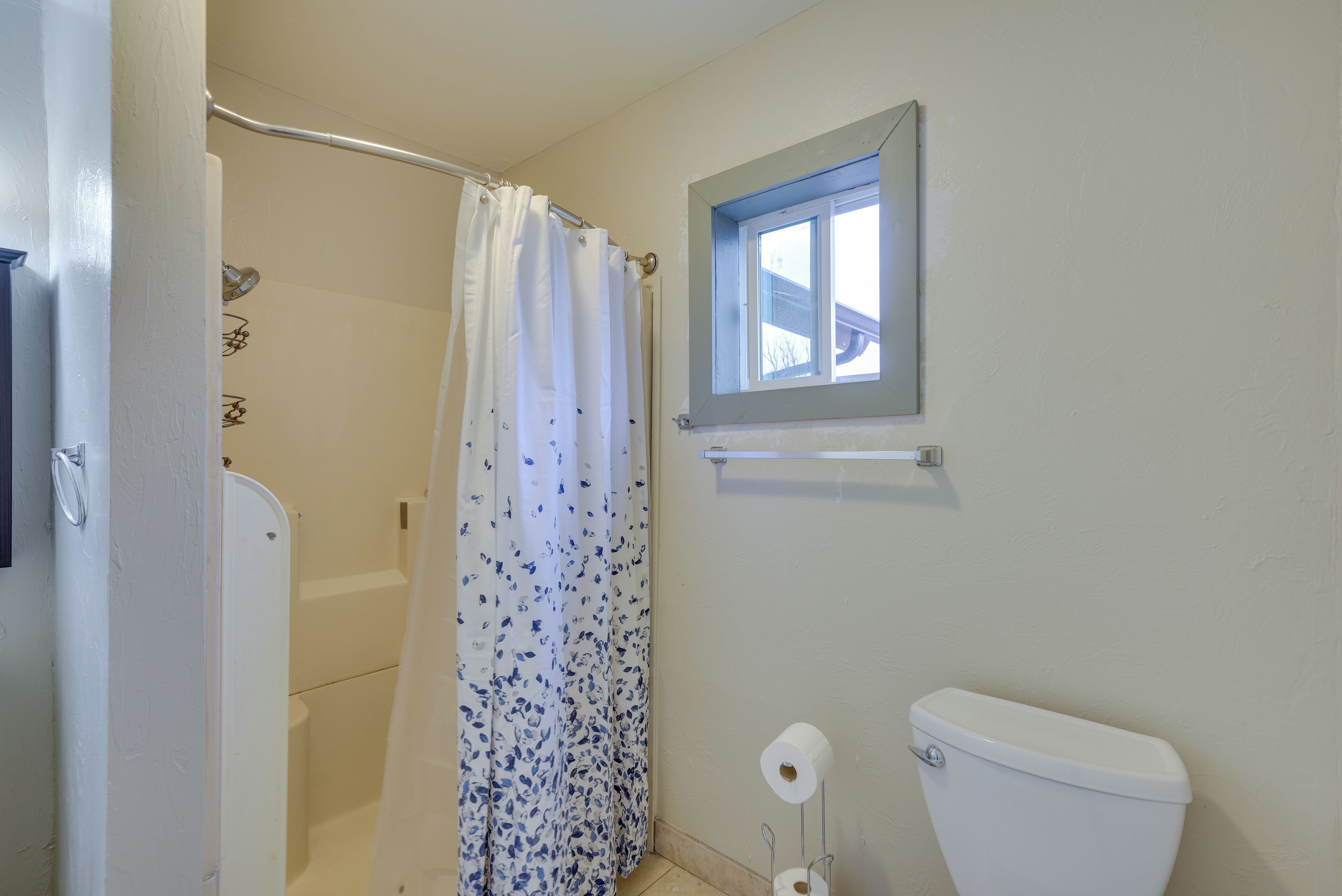 Un baño con ducha, inodoro y ventana.