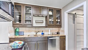 A kitchen with dark wooden cabinets, a stainless steel dishwasher, and a granite countertop.