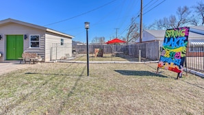 A fenced yard with a green door, a bench, and a sign for Spring Lake Arts District.