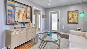 A modern living room with a glass coffee table, a beige sofa, and a large abstract painting on the wall.