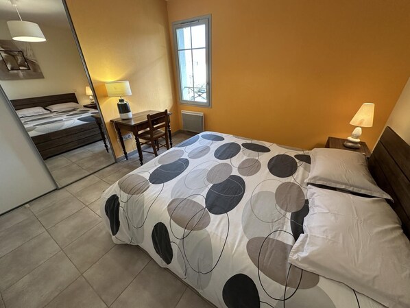 A bedroom with a bed, a desk, and a chair.