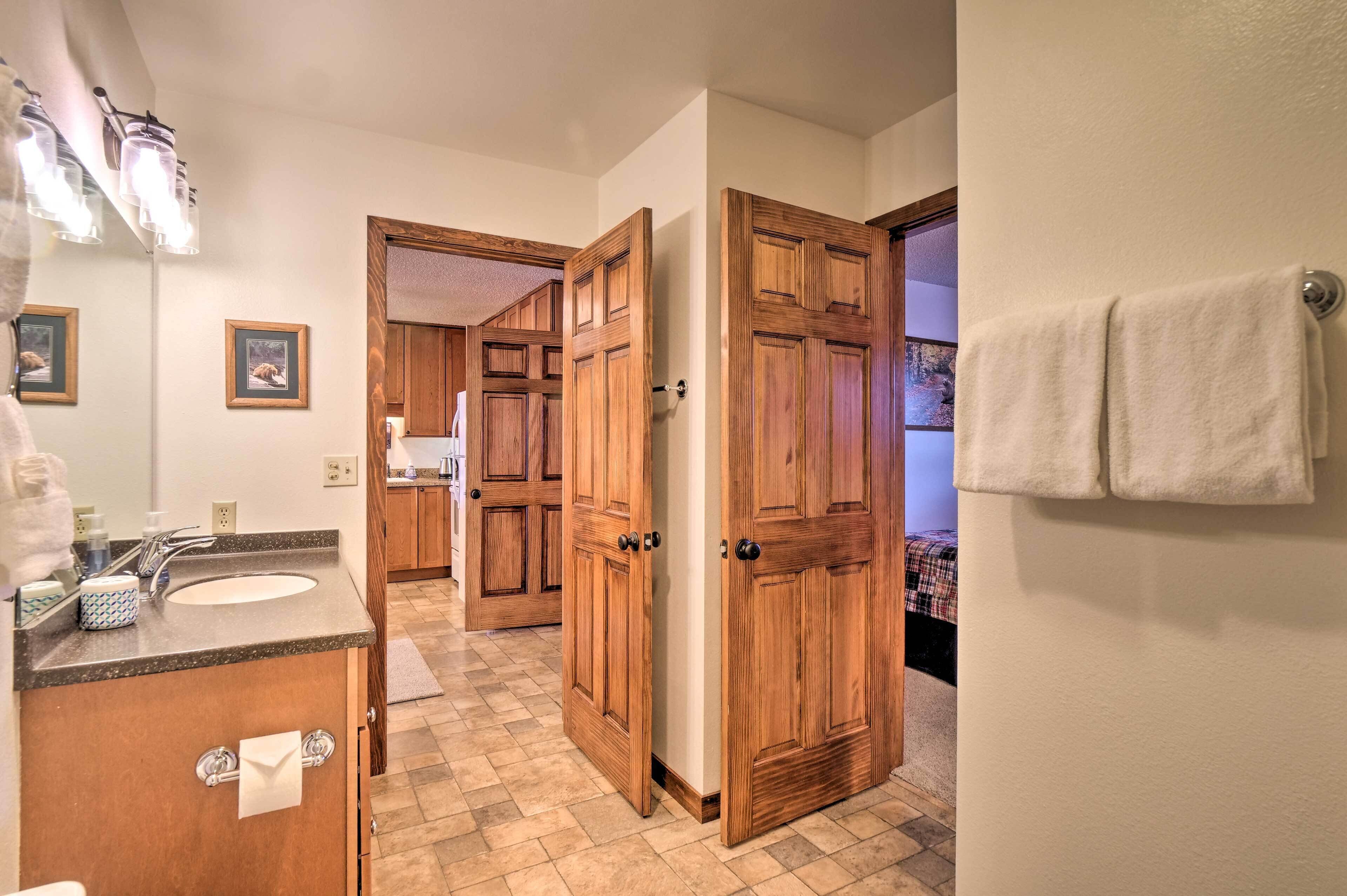 A bathroom with a sink, mirror, wooden cabinets, and a towel rack.