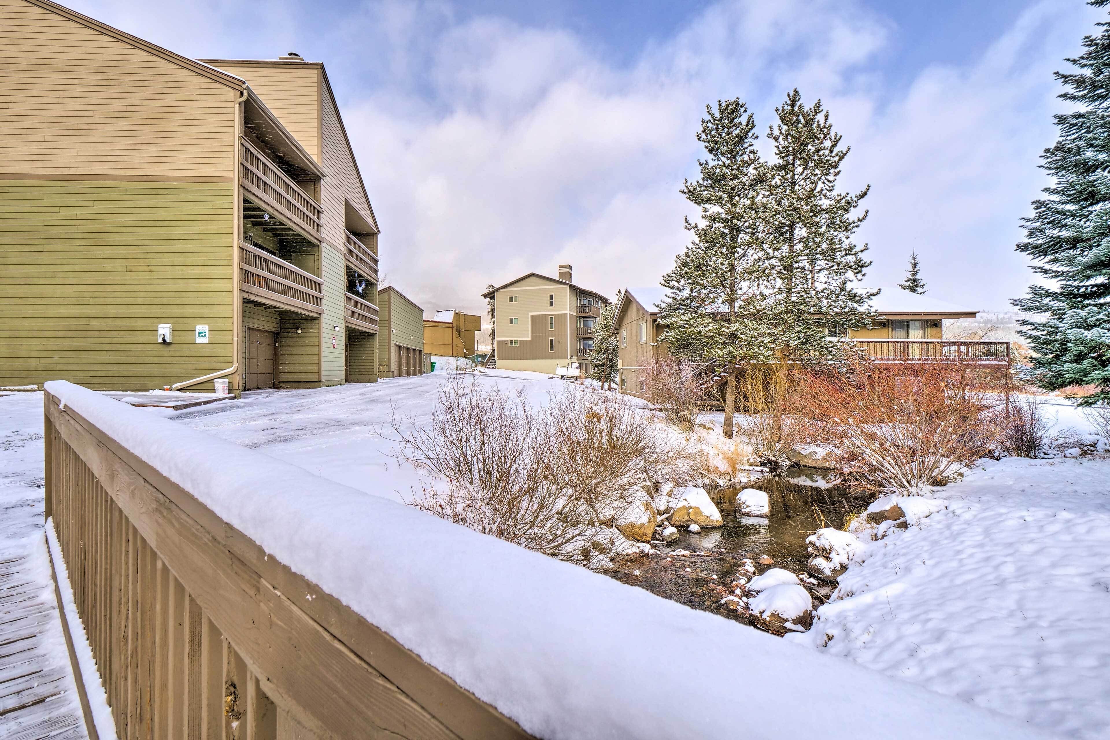 Un quartier résidentiel doté d’une terrasse en bois, d’un petit ruisseau et d’immeubles avec des balcons.