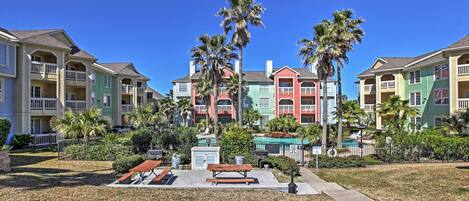 A residential area with colorful houses, a small park with a bench, and palm trees.