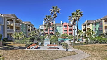 A residential area with colorful houses, a small park with a bench, and palm trees.