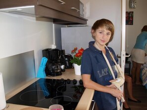 Una cocina con estufa, cafetera y una planta en maceta.