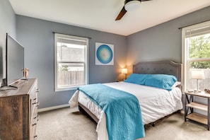 A bedroom with a bed, dresser, windows, and a ceiling fan.