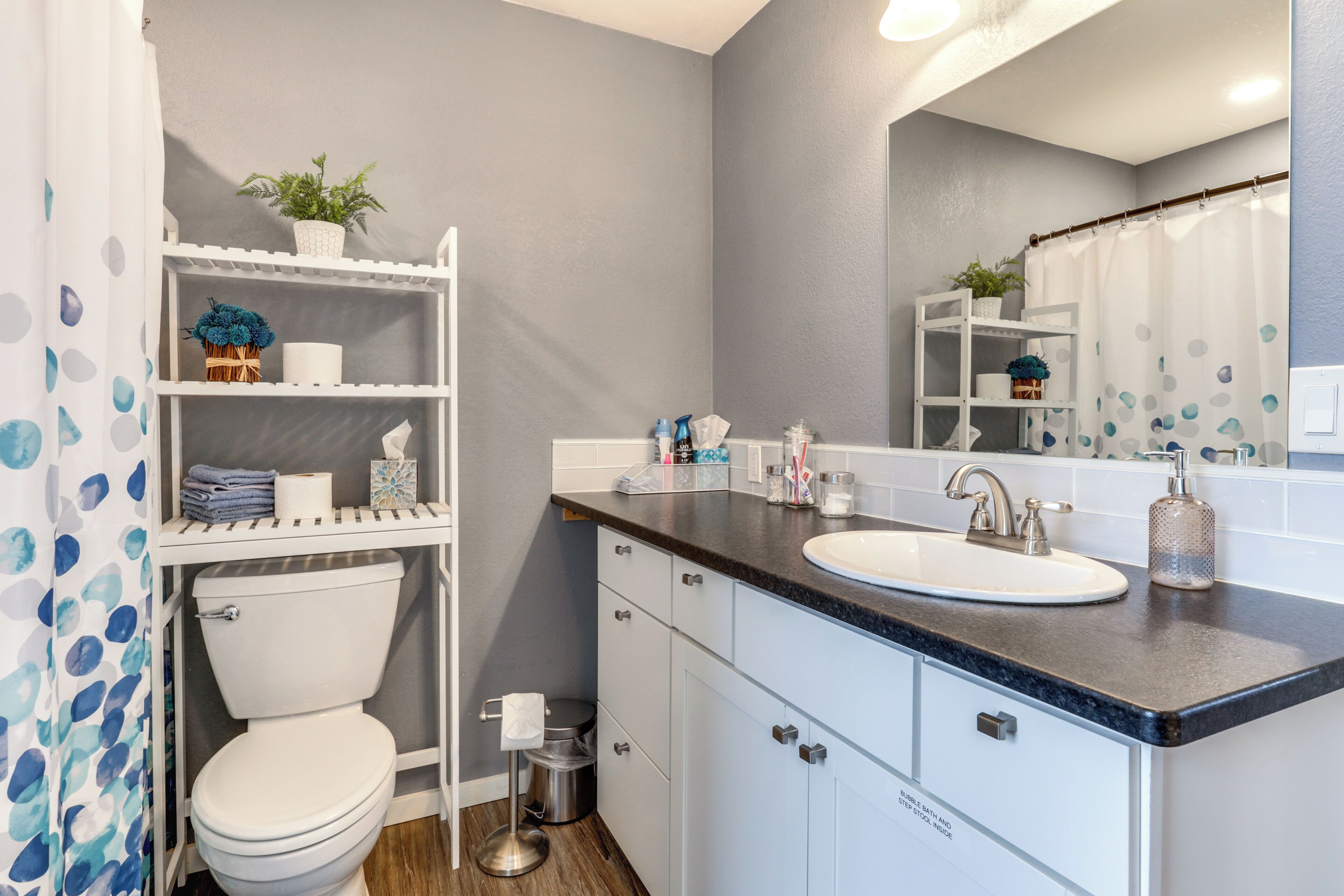 A modern bathroom with a toilet, sink, and shelves.