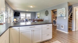 A modern kitchen with white cabinets, a black countertop, and a built-in washing machine. - Charming Mcminnville Home - Walk to Wineries! (McMinnville)