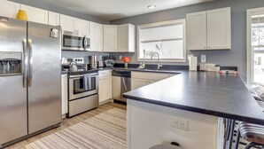 A modern kitchen with stainless steel appliances, white cabinets, and a large island. - Charming Mcminnville Home - Walk to Wineries! (McMinnville)