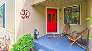 A building with a red door, a welcome mat, a wooden chair, and a small bear statue holding a sign. - Quiet Location! Shasta Lake Home Near Redding (Shasta Lake)