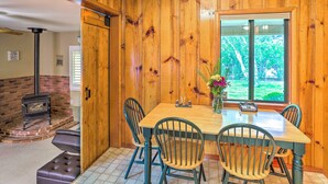 A wooden-paneled dining room with a table and chairs, a fireplace, and a view of greenery outside. - Quiet Location! Shasta Lake Home Near Redding (Shasta Lake)