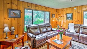 A cozy room with wooden paneled walls, a brown leather sofa, a wooden coffee table, and a lamp. - Quiet Location! Shasta Lake Home Near Redding (Shasta Lake)