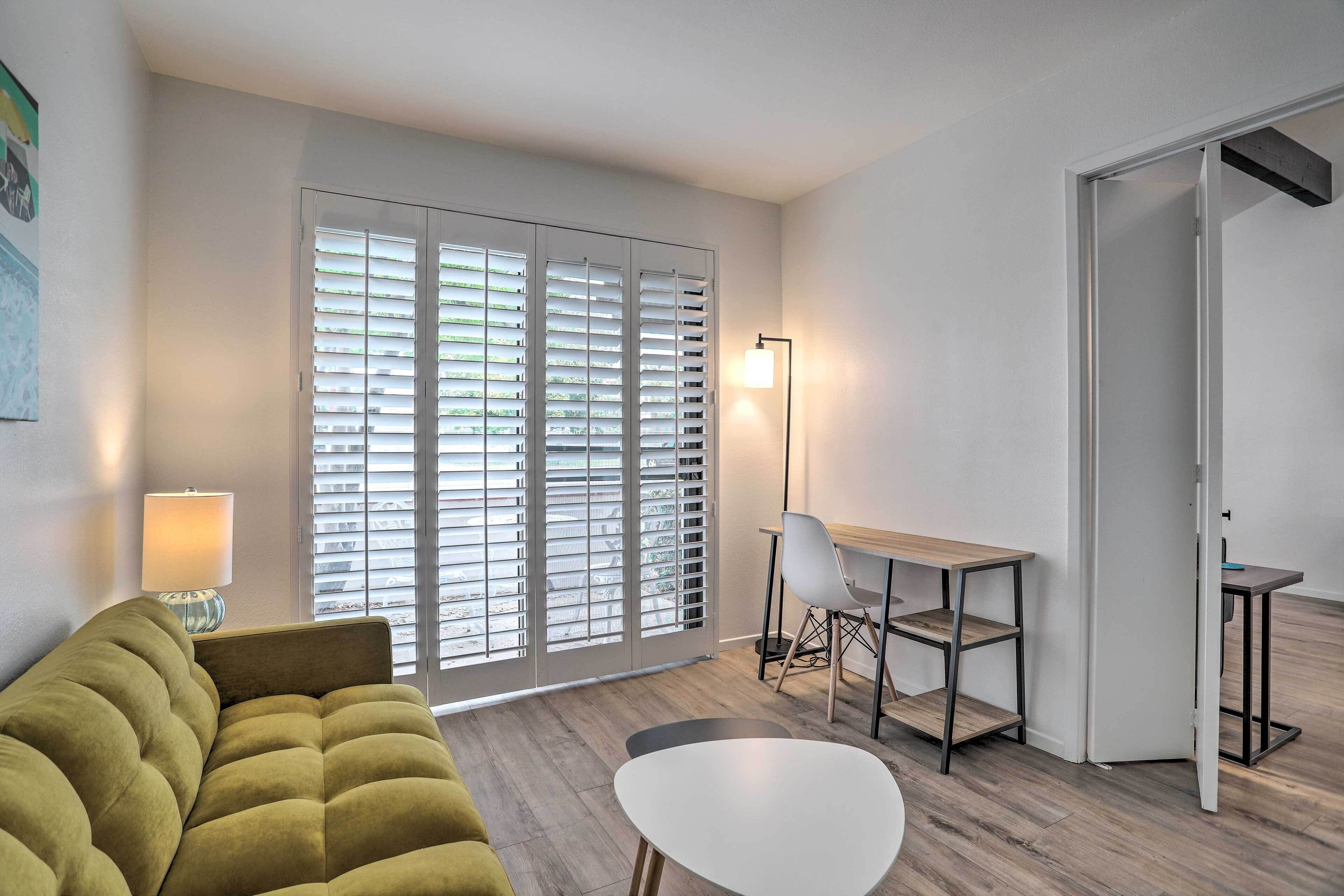 A modern living room with a sofa, a dining table, and a lamp.