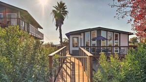 Una casa moderna con terraza de madera, ventanas grandes y una palmera.