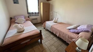 A bedroom with two single beds, a wardrobe, a window, and a bedside table with a lamp. - Le Tastet - Saint LON LES Mines (SAINT LON LES MINES)