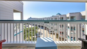 A balcony with a view of a building complex, including a parking area and greenery.