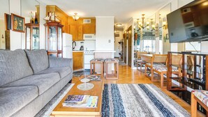 A spacious living area with a gray sofa, wooden coffee table, and a striped rug.