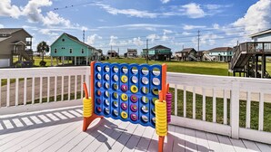 Ein Brettspielaufbau auf einer Holzdielenveranda mit Häusern im Hintergrund.