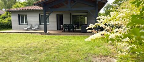 Een modern huis met een overdekt terras, gazon en tuin.